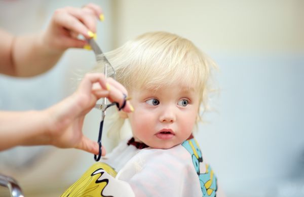 Parrucchiera taglia i capelli ad una bambina bionda