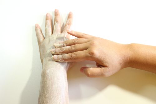 Donna si spalma crema sul braccio e sulla mano