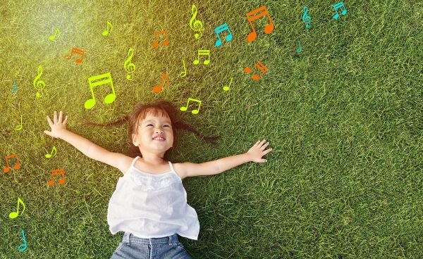 Bambina distesa su un prato verde pensa alla musica
