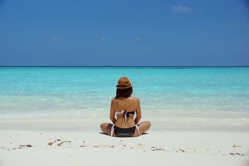 Ragazza seduta sulla spiaggia di fronte al mare