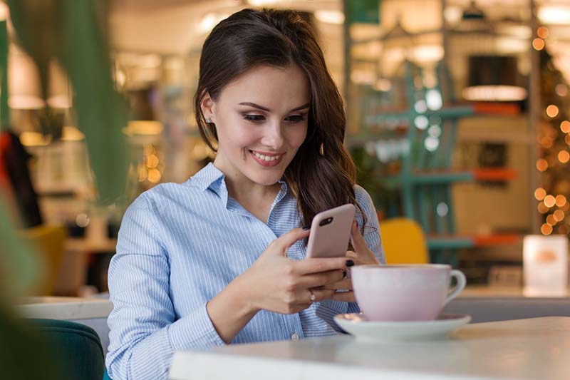 Donna al bar invia un messaggio con lo smartphone 