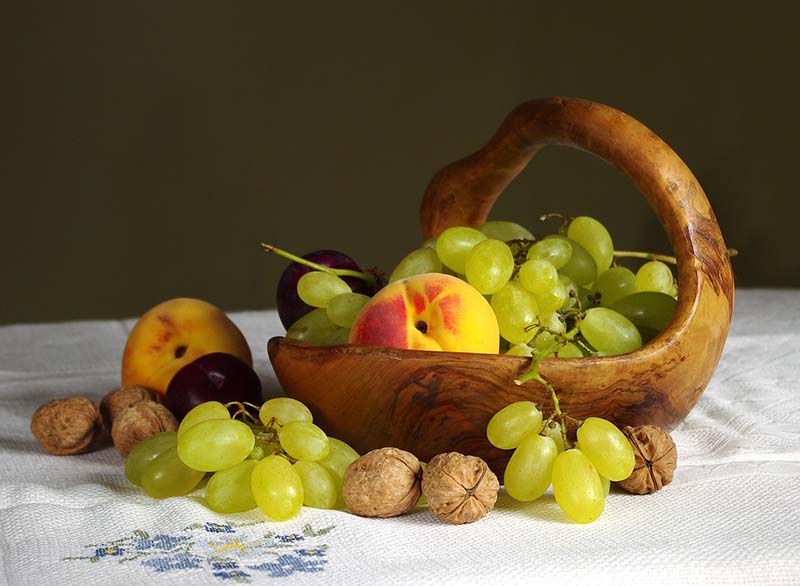 Cesto di frutta con uva, pesche, prugne e noci