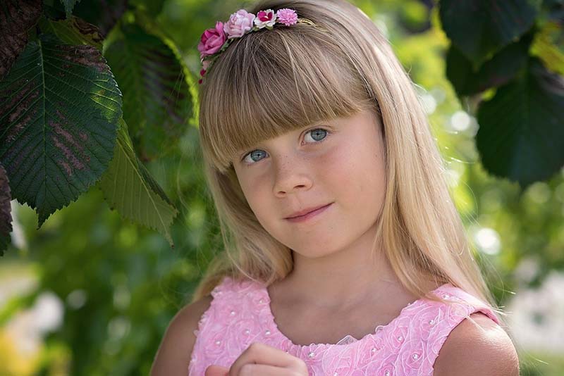 Bambina bionda con occhi azzurri vestita di rosa
