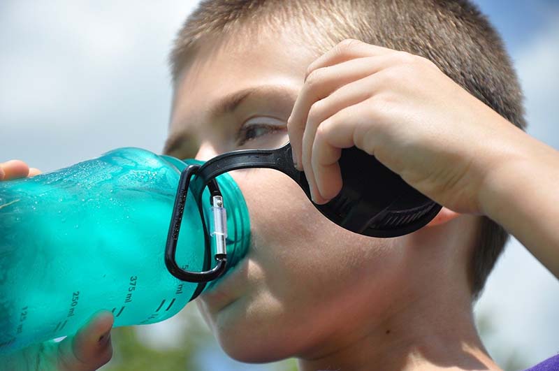 Bambino che beve acqua da una borraccia