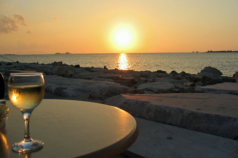 Calice di vino bianco con tramonto sul mare