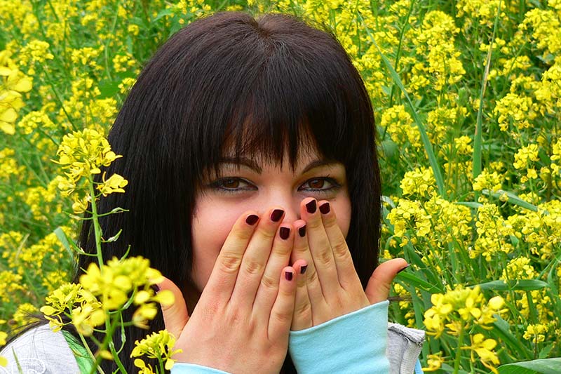 Ragazza con frangia si copre il volto con le mani