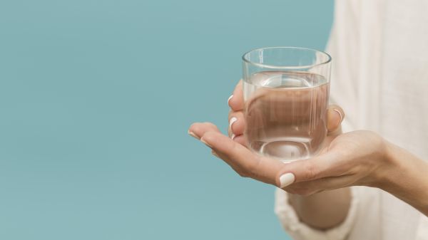 Donna mantiene un bicchiere d'acqua